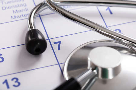 Close-up Of Medical Equipment Stethoscope Over Calendarの写真素材