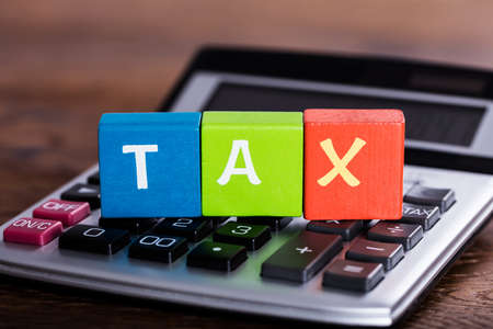 Close-up Of Colorful Blocks With Word Tax Placed Over Calculatorの写真素材