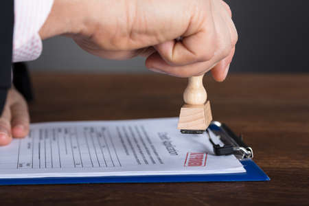 Close-up Of A Person's Hand Stamping On Approved Application Formの写真素材