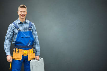 Portrait Of A Happy Male Technician Standing On Gray Backgroundの写真素材