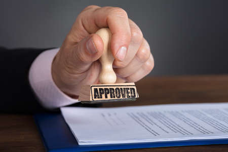 Close-up Of A Person's Hand Stamping On Approved Documentの写真素材