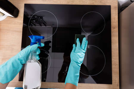 High Angle View Of Person Hand Cleaning Induction Stove In Kitchenの写真素材