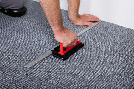 Close-up Of Craftsman's Hands Laying Carpet On The Floorの写真素材