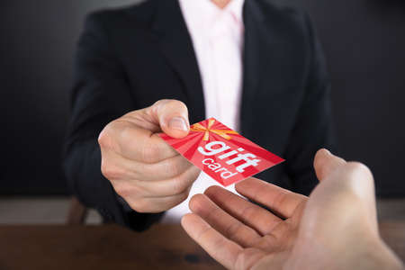 Close-up Of A Businessperson Hands Giving Gift Card To Other Businesspersonの写真素材