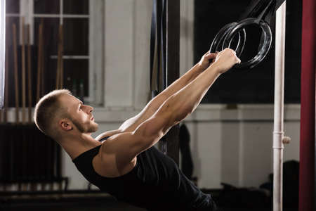 Fitness Man Exercising On Gymnastic Rings In The Gym