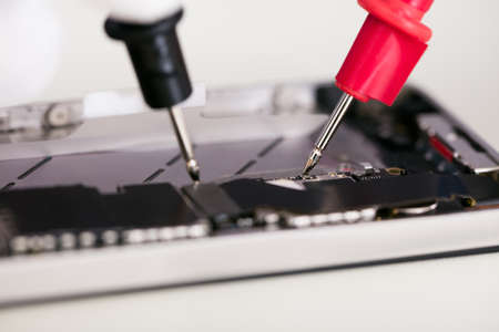 Close-up Of Multimeter Probes Testing Mobile Phone