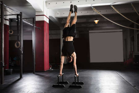 Young Athlete Man Doing Handstand Exercise On Parallel Bar In The Gym