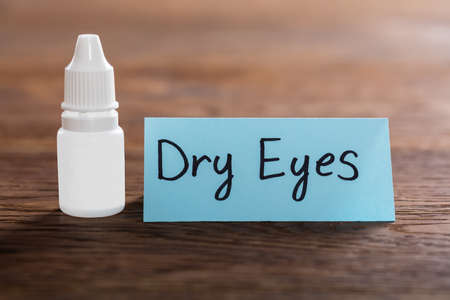 Dry Eyes Concept With Eye Drops On Wooden Deskの写真素材