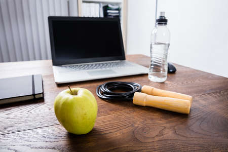 Close-up Of A Workout Equipment Near Laptop On Wooden Deskの写真素材