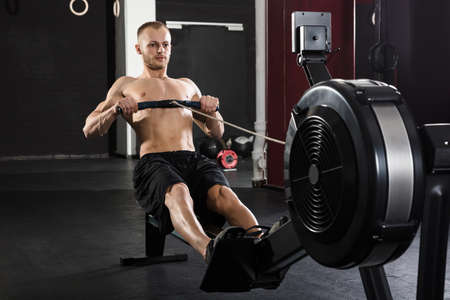 Young Athlete Man Exercising With Row Machine In The Gym
