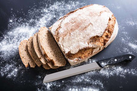 High Angle View Of A Freshly Baked Sliced Bread With Knife And Flour