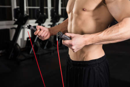 Close-up Of A Young Athlete Man Holding Skipping Rope In The Gym