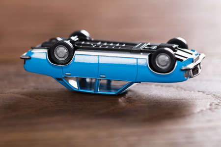 Close-up Of A Crashed Toy Car On Wooden Deskの写真素材