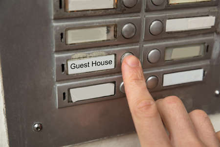 Close-up Of A Person Clicking On  Door Bell Button Showing Guesthouse