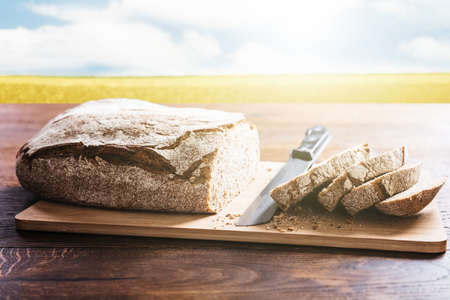 Sliced Bread On Cutting Board With A Knife At Wooden Desk