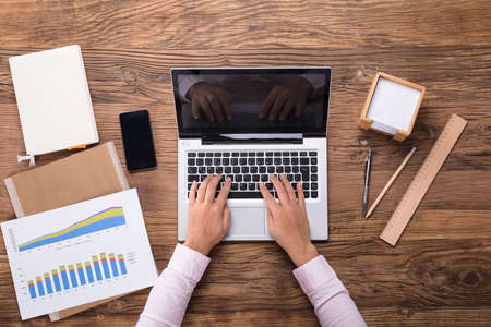 High Angle View Of Businesswoman Typing On Laptop At Workplaceの写真素材