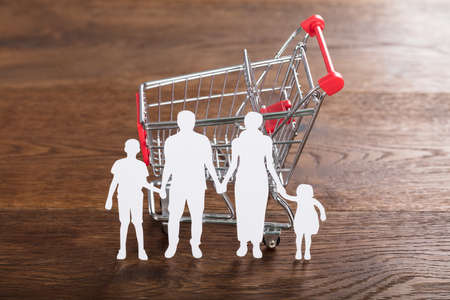 Close-up Of A Family Paper Cut With Shopping Cart On Wooden Deskの写真素材