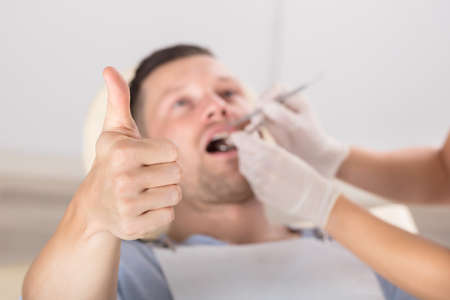 Close-up Of A Man Showing Thumb Up Sign While Having Dental Checkup In A Clinic