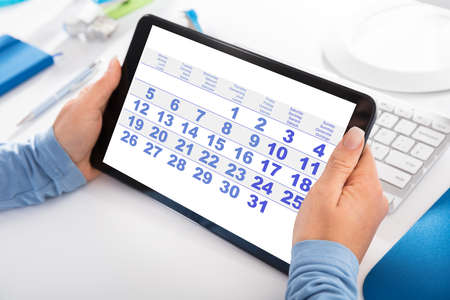Close-up Of A Woman Looking At Calendar On Digital Tabletの写真素材