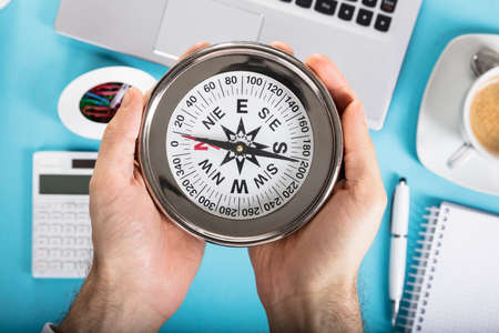 Close-up Of A Person Holding Compass In Hand At Workplaceの写真素材