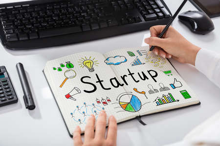 Close-up Of A Businesswoman Drawing Start Up Chart On Notebook Over Desk