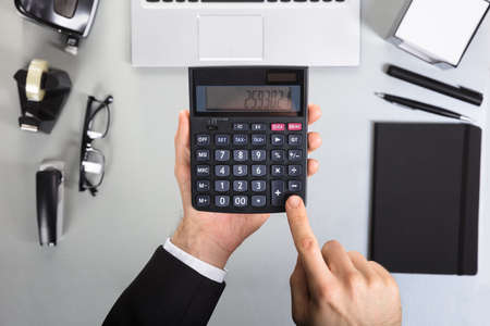 Close-up Of A Businessman Using Calculator In Office