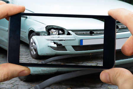 Close-up Of A Person's Hand Taking Photo Of Car Accident Through Smartphoneの写真素材