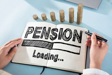 Elevated View Of A Businessperson Drawing Pension Chart On Notebook With Coin Stack On Deskの写真素材