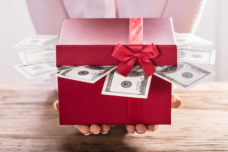 Close-up Of A Woman Holding Gift Box Of Us Dollar Billsの写真素材