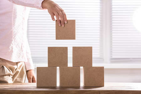 Close-up Of A Woman Placing Block On Deskの写真素材