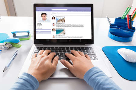 Close-up Of A Businesswoman Chatting On Social Website On Laptop At Workplaceの写真素材