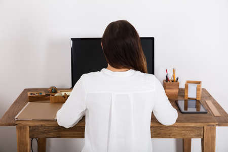 Rear View Of A Woman Using Computer At Homeの写真素材