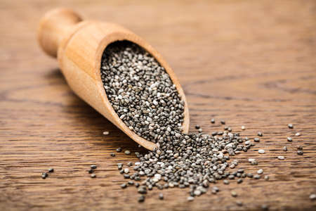 Raw Chia Seeds On Wooden Scoop On Wooden Backgroundの写真素材