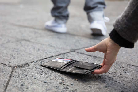 Close Of A Person Picking Up A Lost Wallet On Streetの写真素材