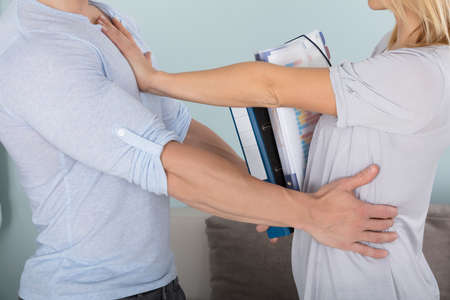 Close-up Of A Woman Holding Folders Pushing A Man Backの写真素材