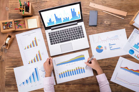 Businesswoman Analyzing Various Graph Placed On Desk