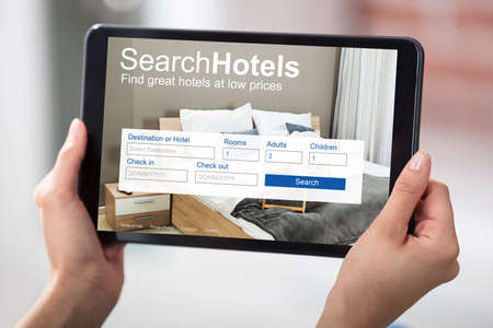 Woman Holding A Digital Tablet Screen Showing Online Low Priced Hotelsの写真素材