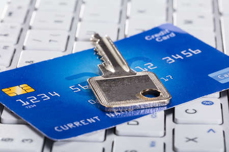 Close-up Of A Silver Key And Credit Card On Keyboard