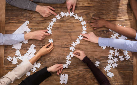 High Angle View Of Businesspeople Making Question Mark Sign With Jigsaw Puzzleの写真素材