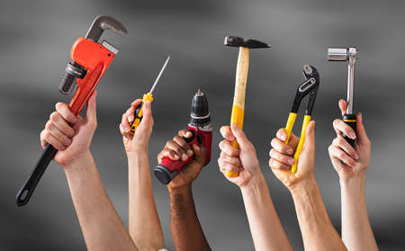 Hands Holding Work Tools Against The Gray Background