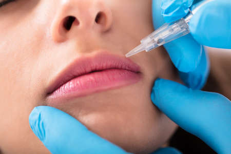 Cosmetologist Applying Permanent Make Up On Woman's Lips In Beauty Spa