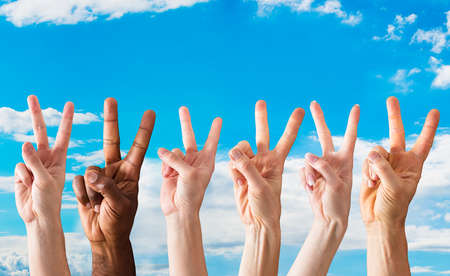 Group Of Hands Showing The Sign Of Peace Against The Blue Sky
