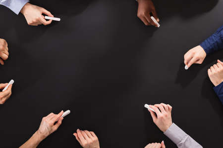 Overhead View Of Hands Drawing With Chalk On Blackboardの写真素材