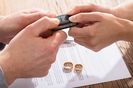 Couple's Fighting For Car While Signing Divorce Agreement With Gold Wedding Ringsの写真素材