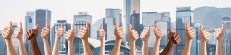 Row Of Hands Showing Thumb Up Sign Against The City Skylineの写真素材