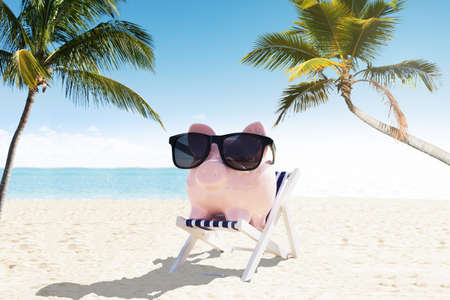 Piggybank With Sunglasses On Deck Chair Enjoying The Holiday At Beachの写真素材