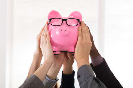 Group Of Businesspeople Hands Holding Pink Piggy Bank With Eye Glassesの写真素材