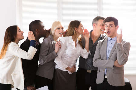 Business Colleague Whispering Secret Gossip To An Amazed Shocked Man With Wide Open Mouth