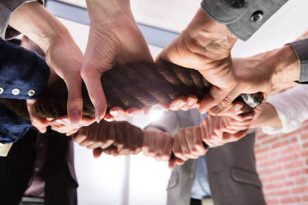 Close-up Of Businesspeople Hands Holding The Rope Forming A Circle