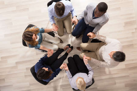 Overhead View Of People Sitting On Chair In Circle Supporting Each Other